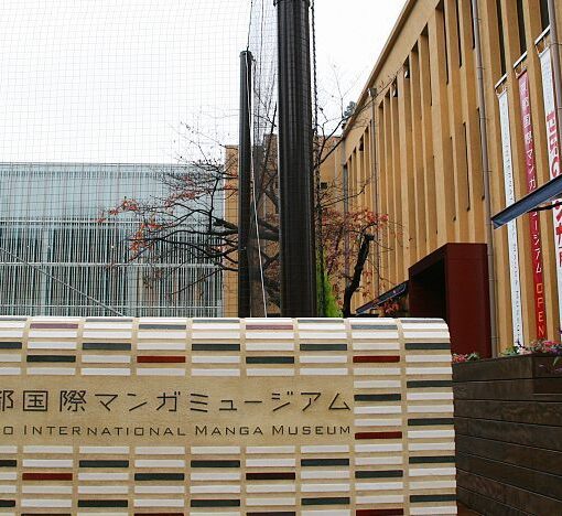 A low brick wall bears the words "Kyoto International Manga Museum" in English and Japanese in front of a repurposed brick two-storey school building.