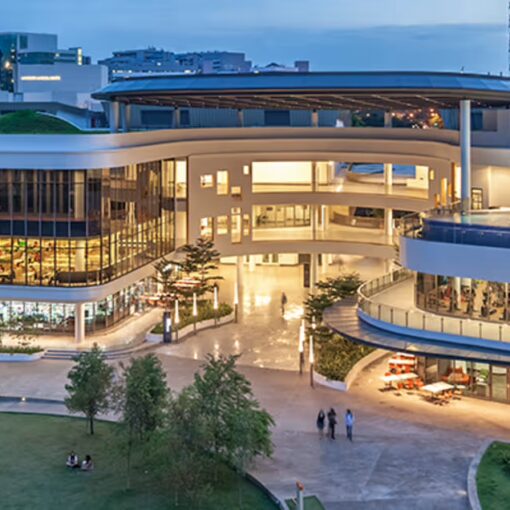 A two-level conference center at dusk overlooking a greensward.